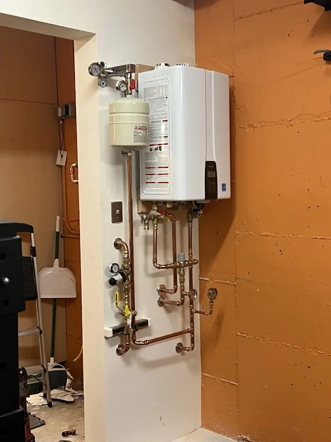Plumbing technician inspecting water heater connections in Essex